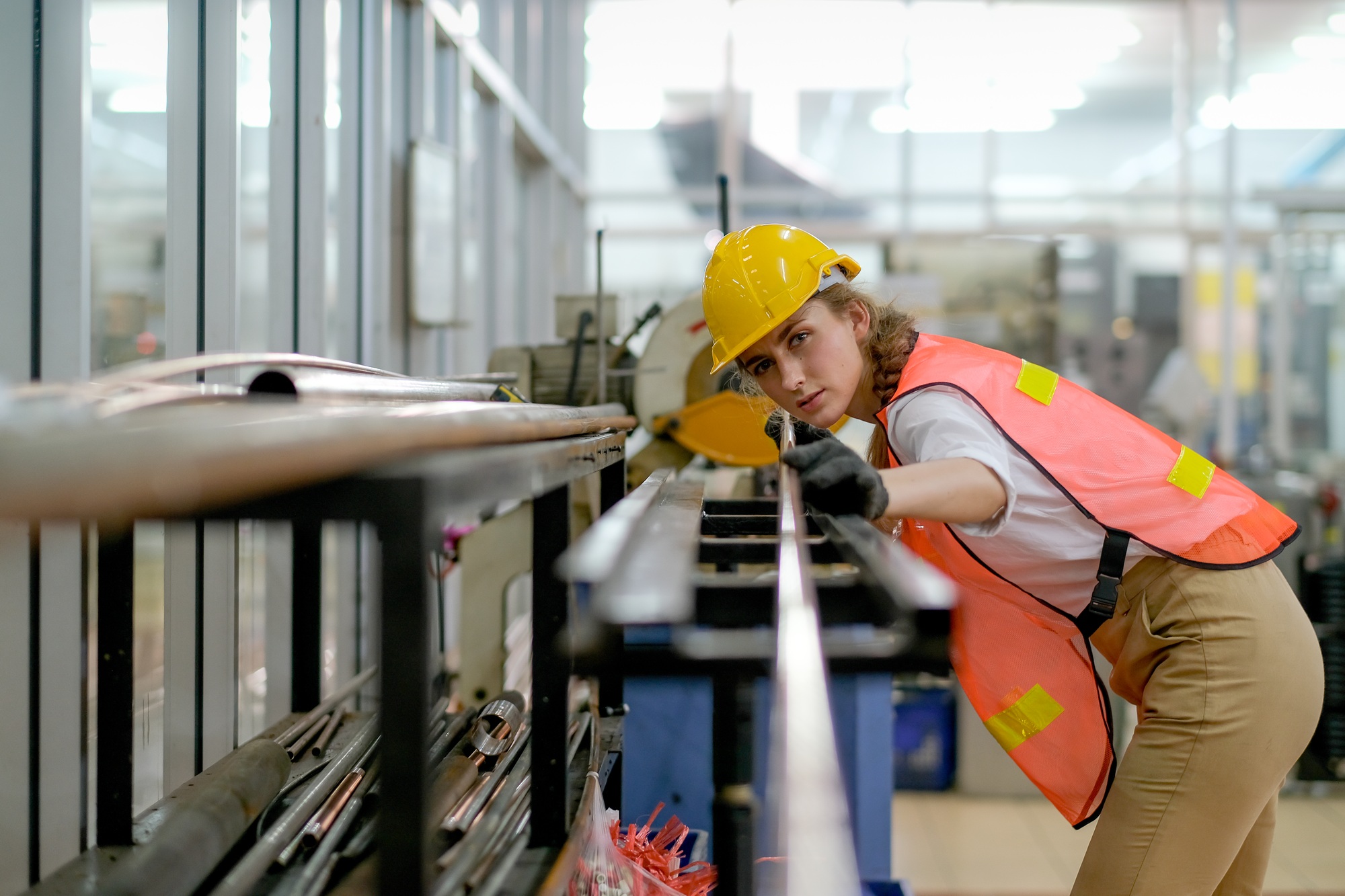 Factory technician or worker woman with safety uniform hold copper tube and look to camera